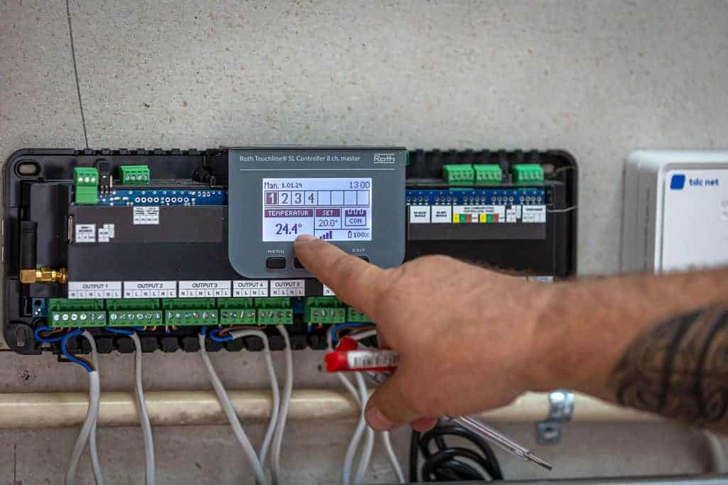 En finger trykker på en knap på et digitalt kontrolpanel til varme